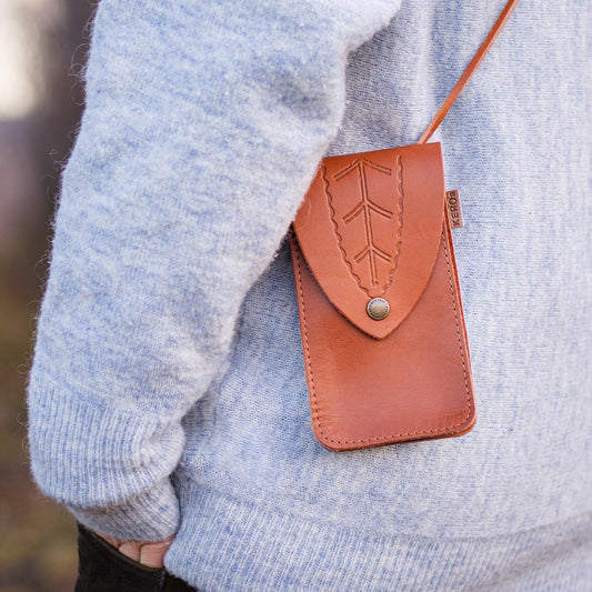 Mobilväska från KERO's hängandes på modell som en handväska i färgen natur.